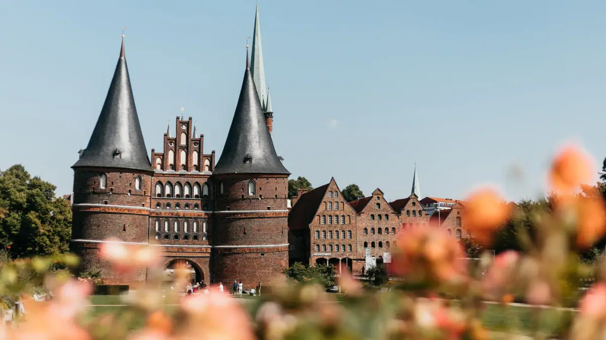 Een gebouw met torens en een grasveld op de achtergrond.