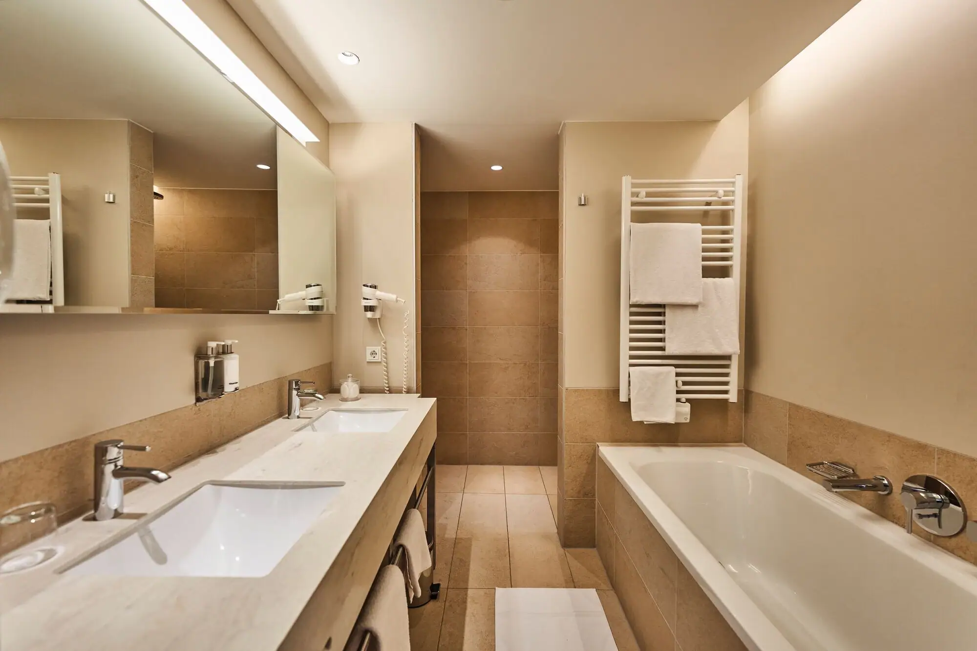 Badkamer met ligbad en wastafel, voorzien van kranen en tegels.