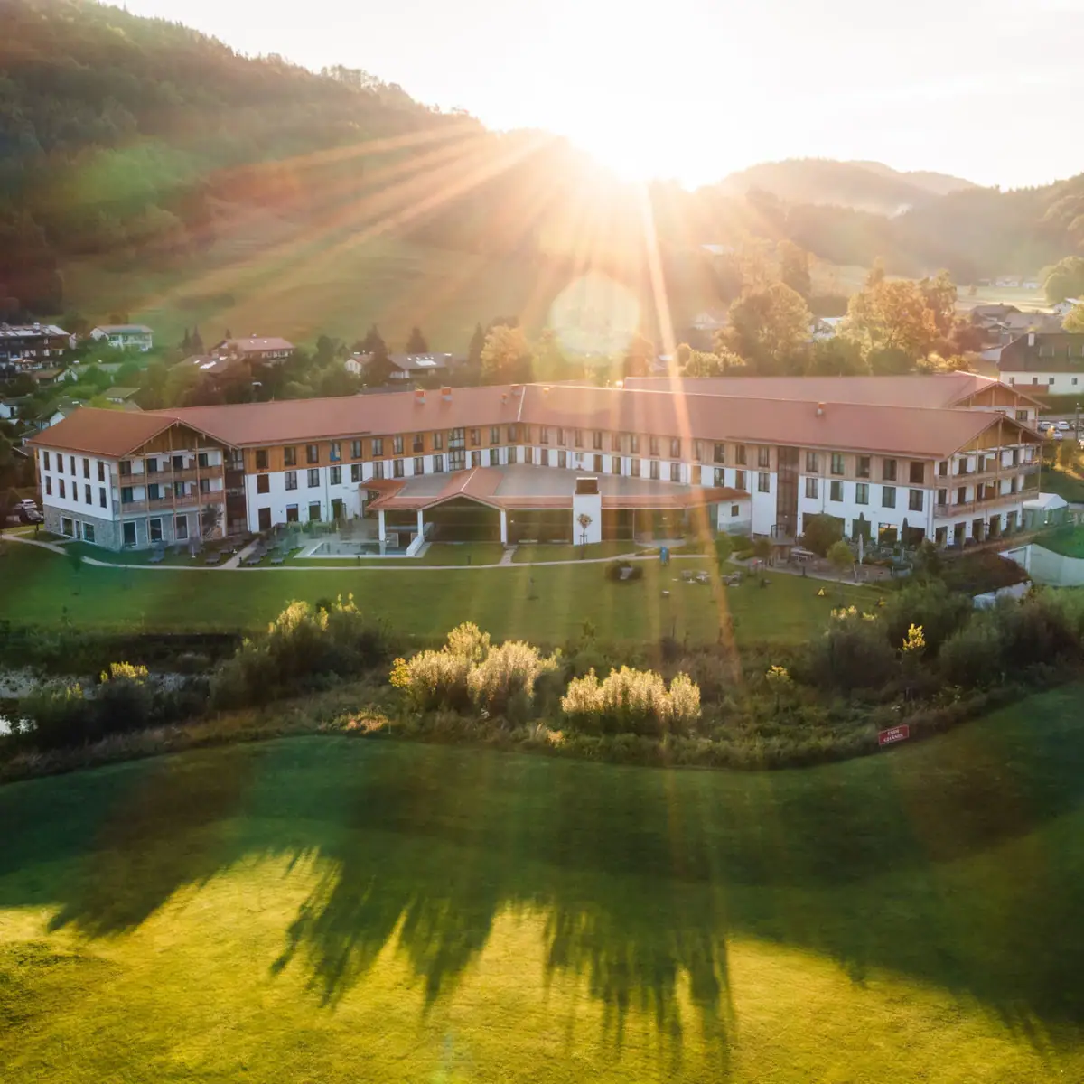 aja Ruhpolding Een groot gebouw met een groot grasveld en een parkeerplaats.