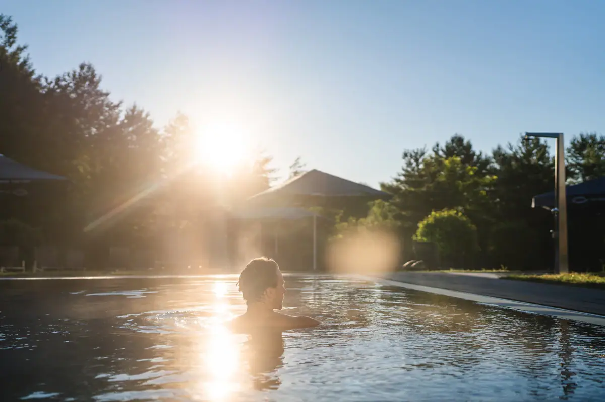 aja spa Een persoon in een zwembad waar de zon op schijnt.
