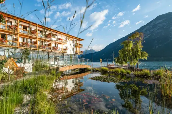 Een gebouw naast een waterlichaam met bomen en wolken in de lucht.