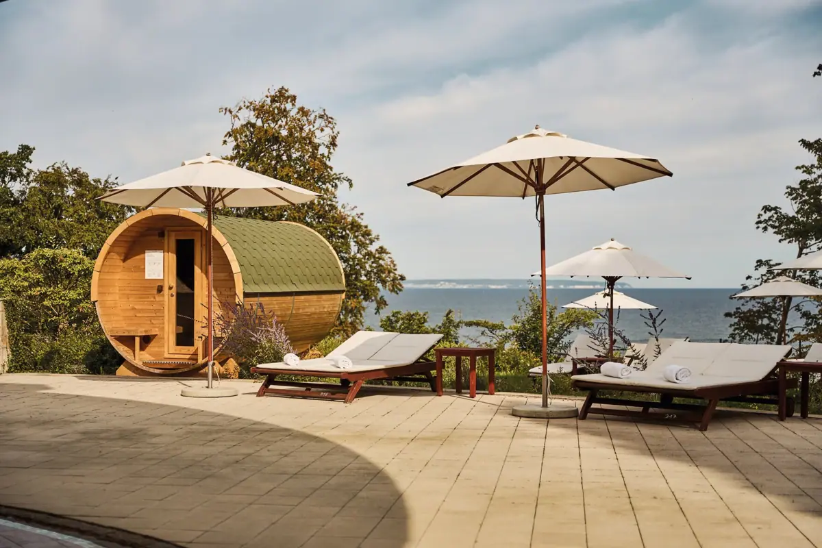 Ligstoelen en parasols naast een vat-sauna aan het water