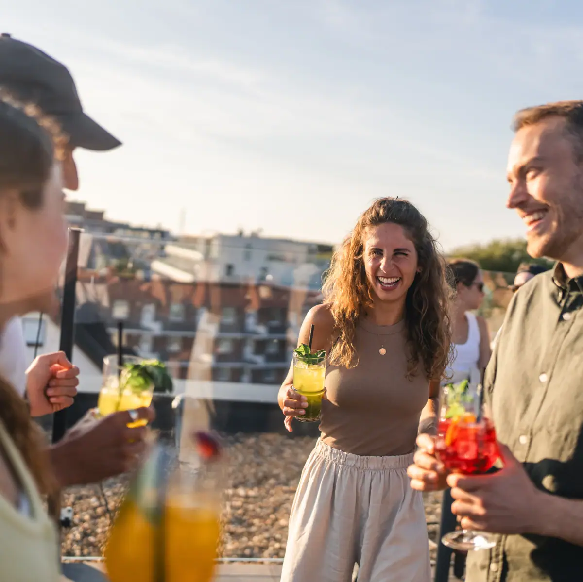 Groep feestende mensen met cocktails op een dakterras