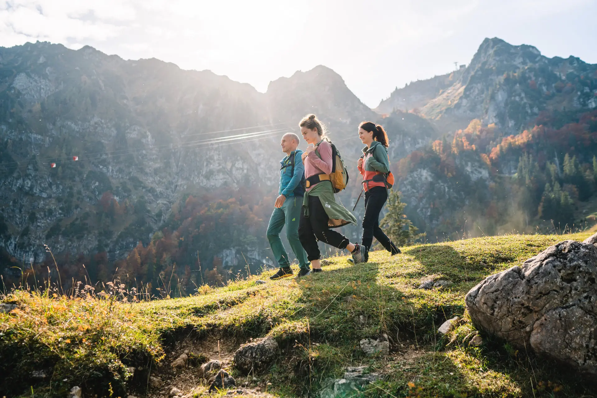 Een groep mensen aan het wandelen op een heuvel met bergen op de achtergrond.