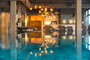 Ein moderner Innenpool Bereich mit Liegen und Lampen im Hintergrund.
