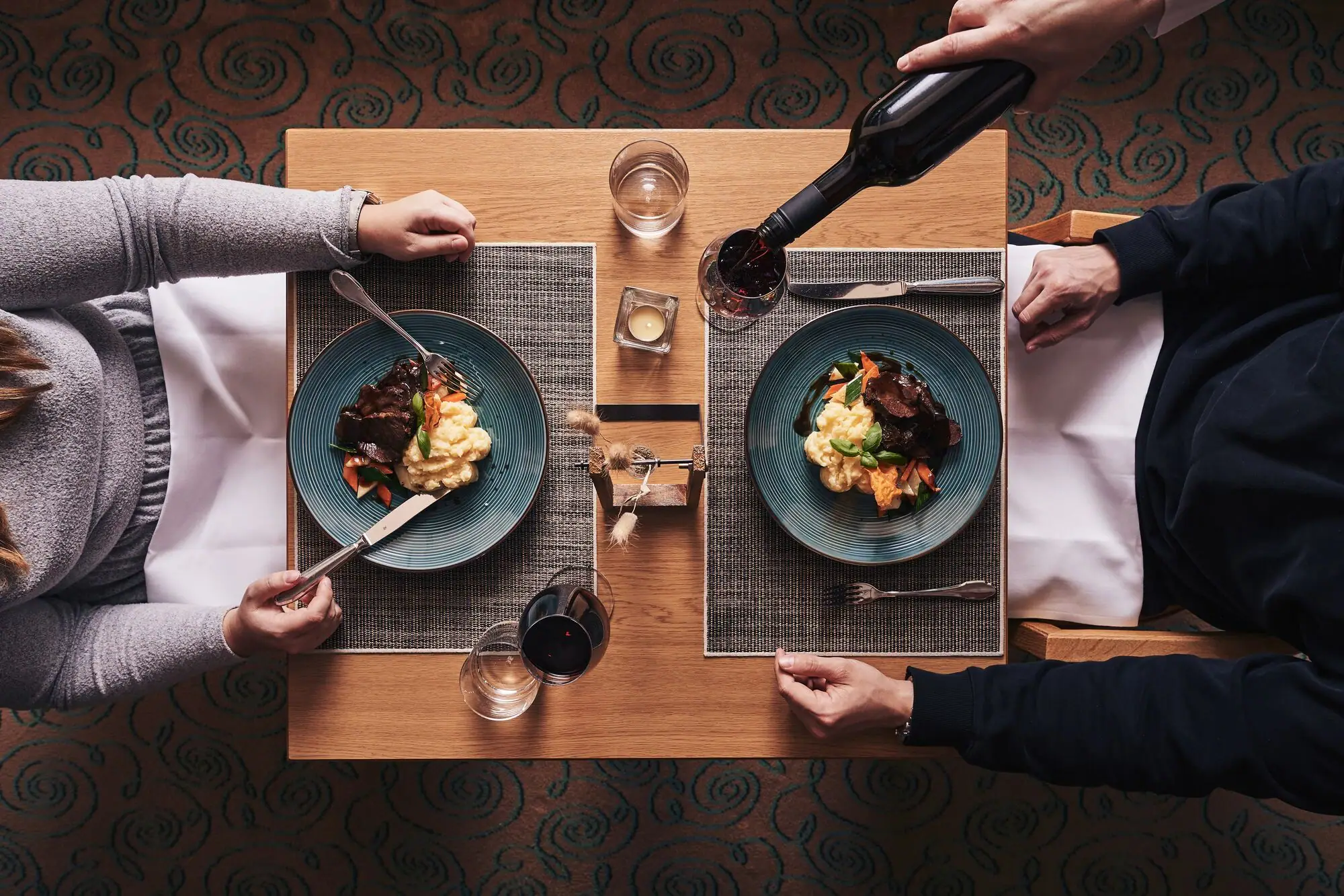Iemand houdt een fles wijn vast en eet voedsel.