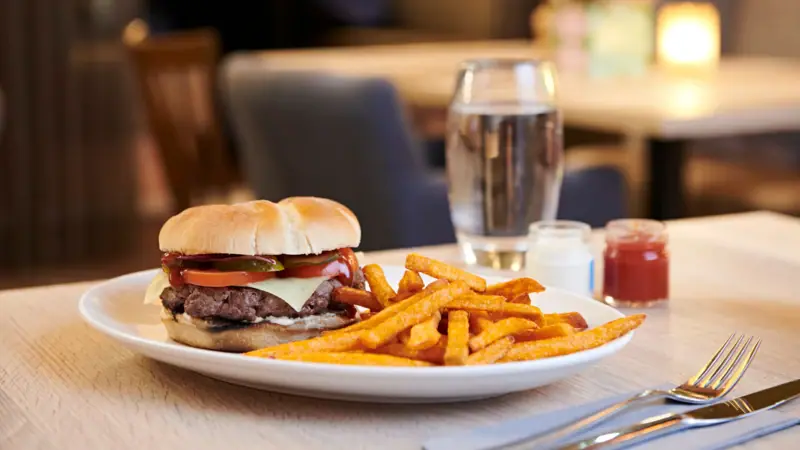 Buger Een bord chips en een broodje op tafel.