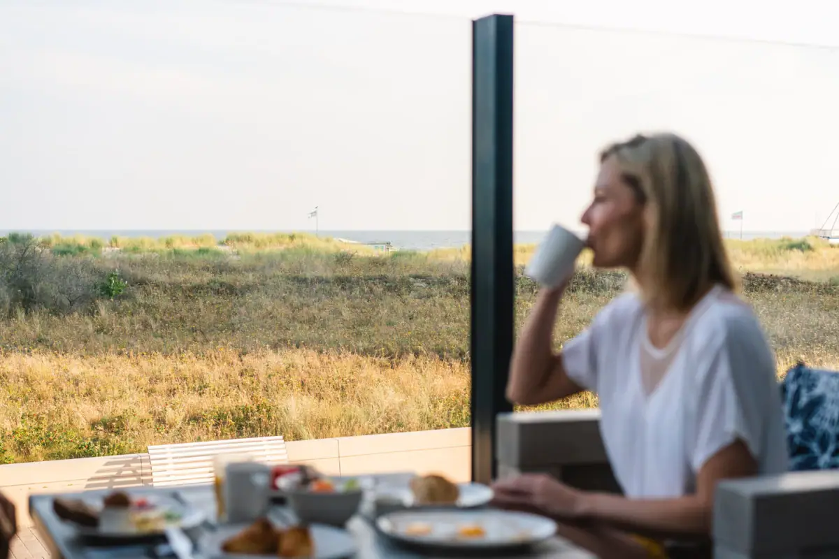 Een vrouw zit aan een tafel met een kop koffie.