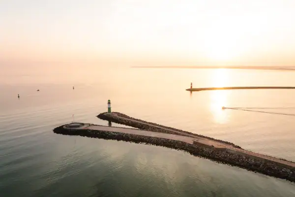 Warnemünde Leuchtturm Ein langer Pier mit einem Leuchtturm darauf.