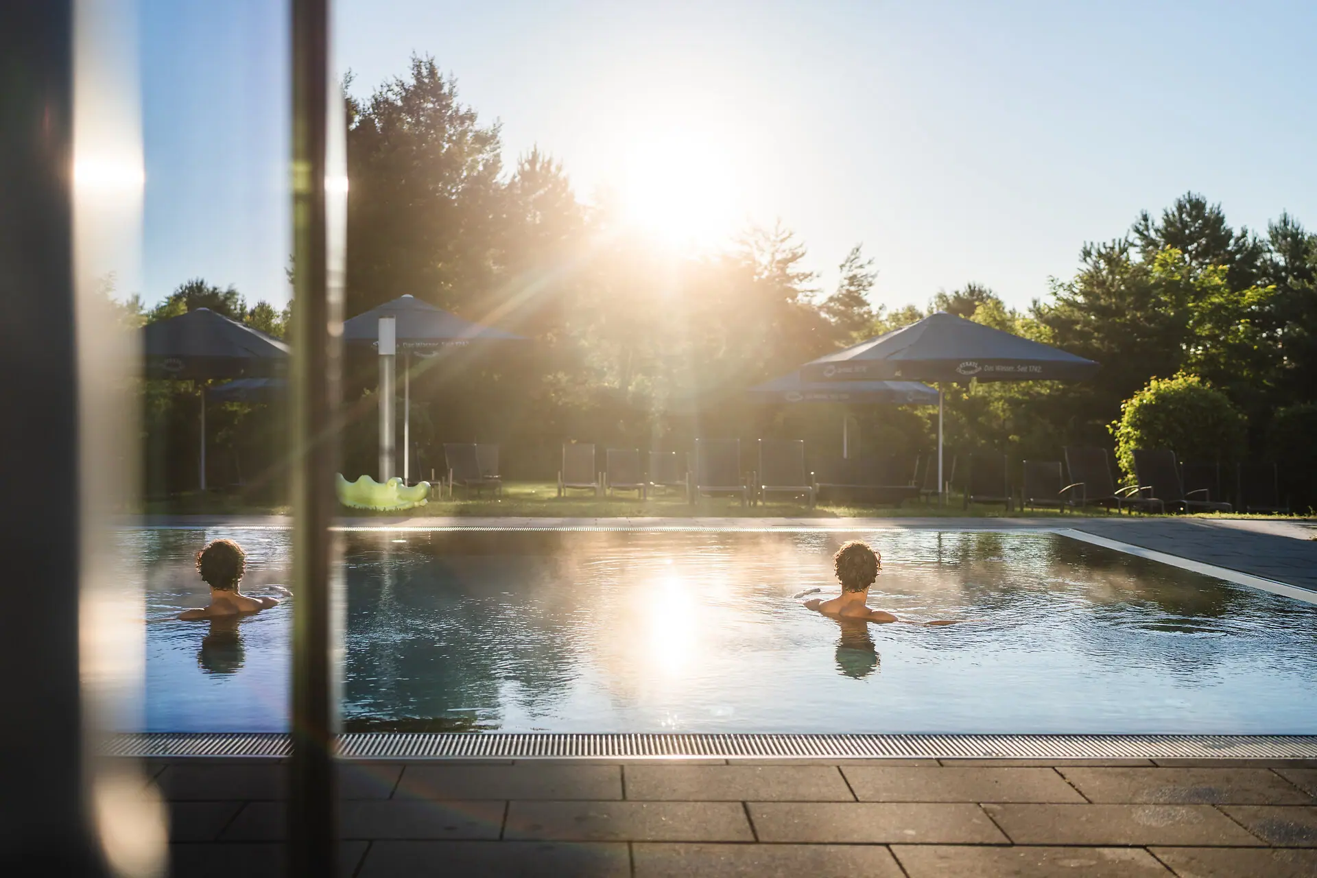 Iemand zwemt in een buitenzwembad in de zon.
