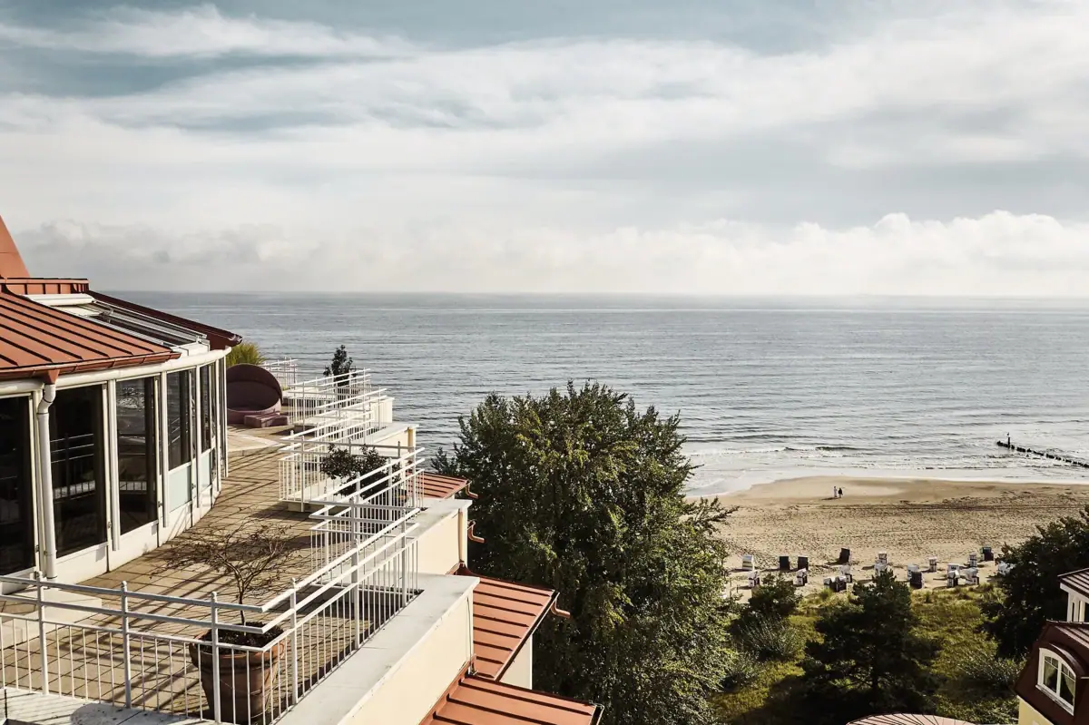 Een strand met een gebouw en een watermassa.