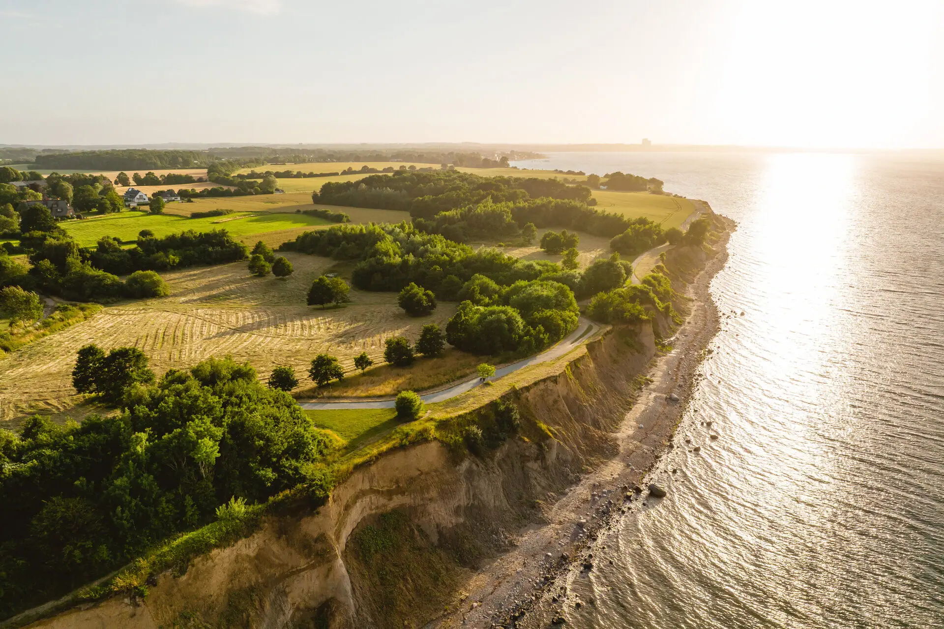 Luchtfoto van een strand met een grasveld en bomen en een steile oever.