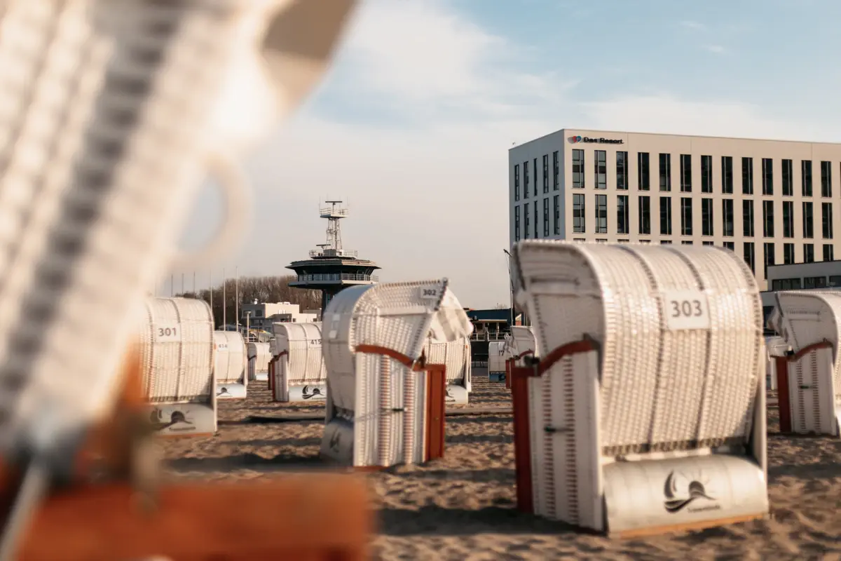 Groep witte strandstoelen op het strand onder een blauwe lucht met sluierwolken.