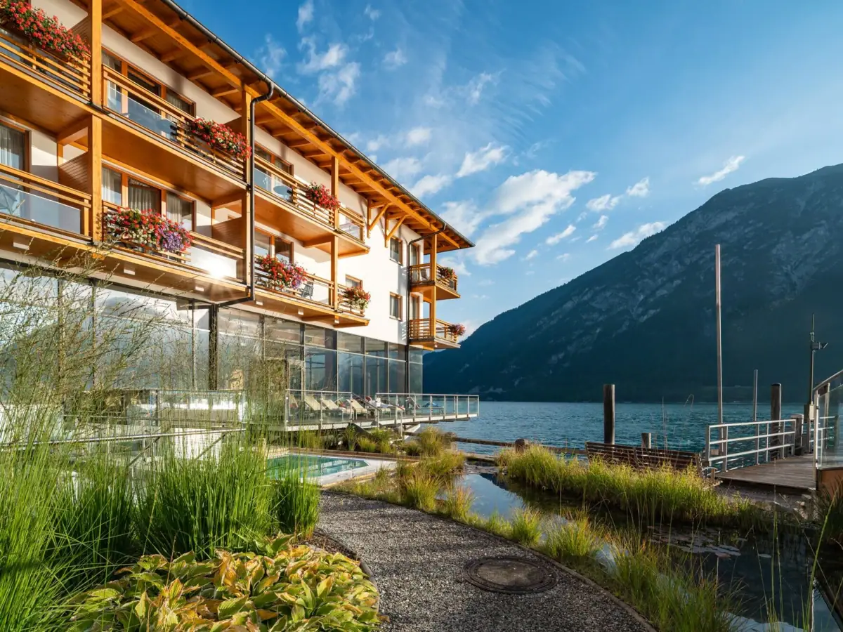 aja Fürstenhaus aan de Achensee Een gebouw met een meer en bergen op de achtergrond.