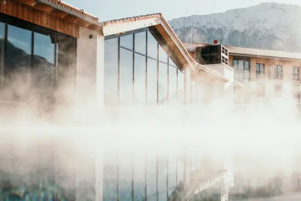 Een gebouw aan het water met een berg op de achtergrond.