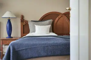 Senior-Suite Ein Bett mit einer blauen Decke und einem weißen Kissen.