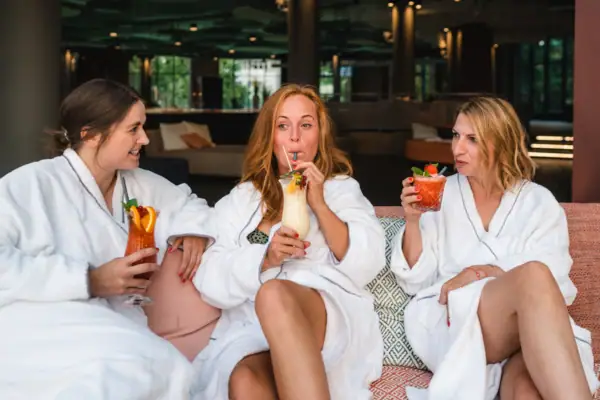 Wellnessruimte bij de aja Warnemünde Een groep vrouwen in witte badjassen drinkt cocktails.