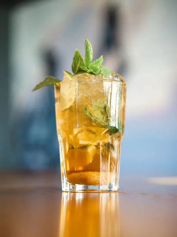 Een glas met een cocktail en muntblaadjes.