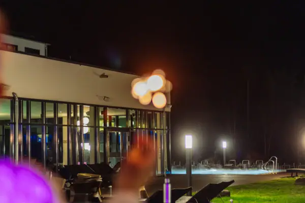 Een persoon staat 's nachts voor een gebouw.