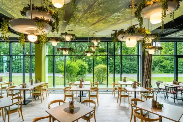 Een kamer met tafels, stoelen en planten die aan het plafond hangen.