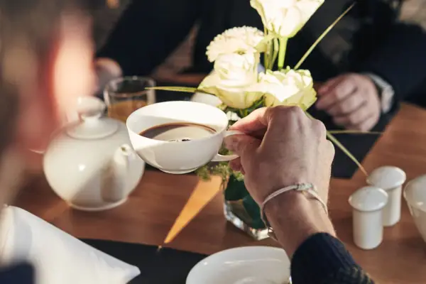 Een persoon houdt een kop koffie vast.