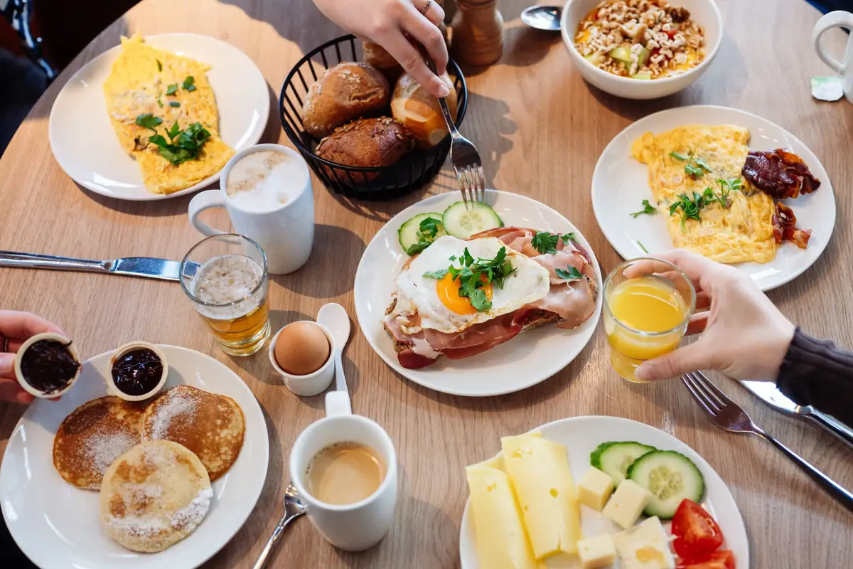 Ontbijt Een tafel vol eten, met een grote verscheidenheid aan gerechten en gedekte plaatsen.