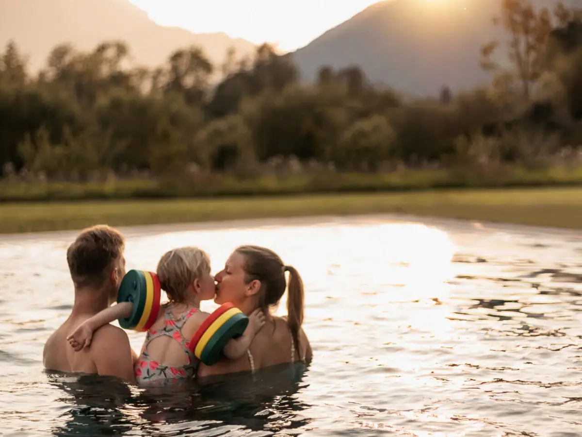 Een groep mensen in het zwembad, een kind geeft een kus.