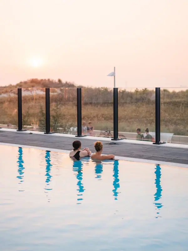 Buitenzwembad bij aja Warnemünde Twee mensen zwemmen in een buitenzwembad.