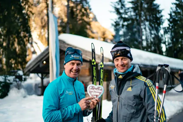 Twee mannen houden ski's vast en glimlachen.