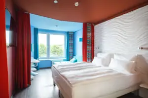 Een kamer met twee bedden en rode gordijnen.