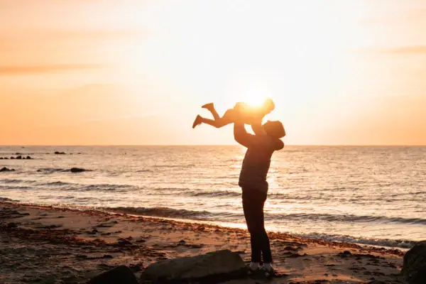 Een vrouw houdt een baby vast op het strand.