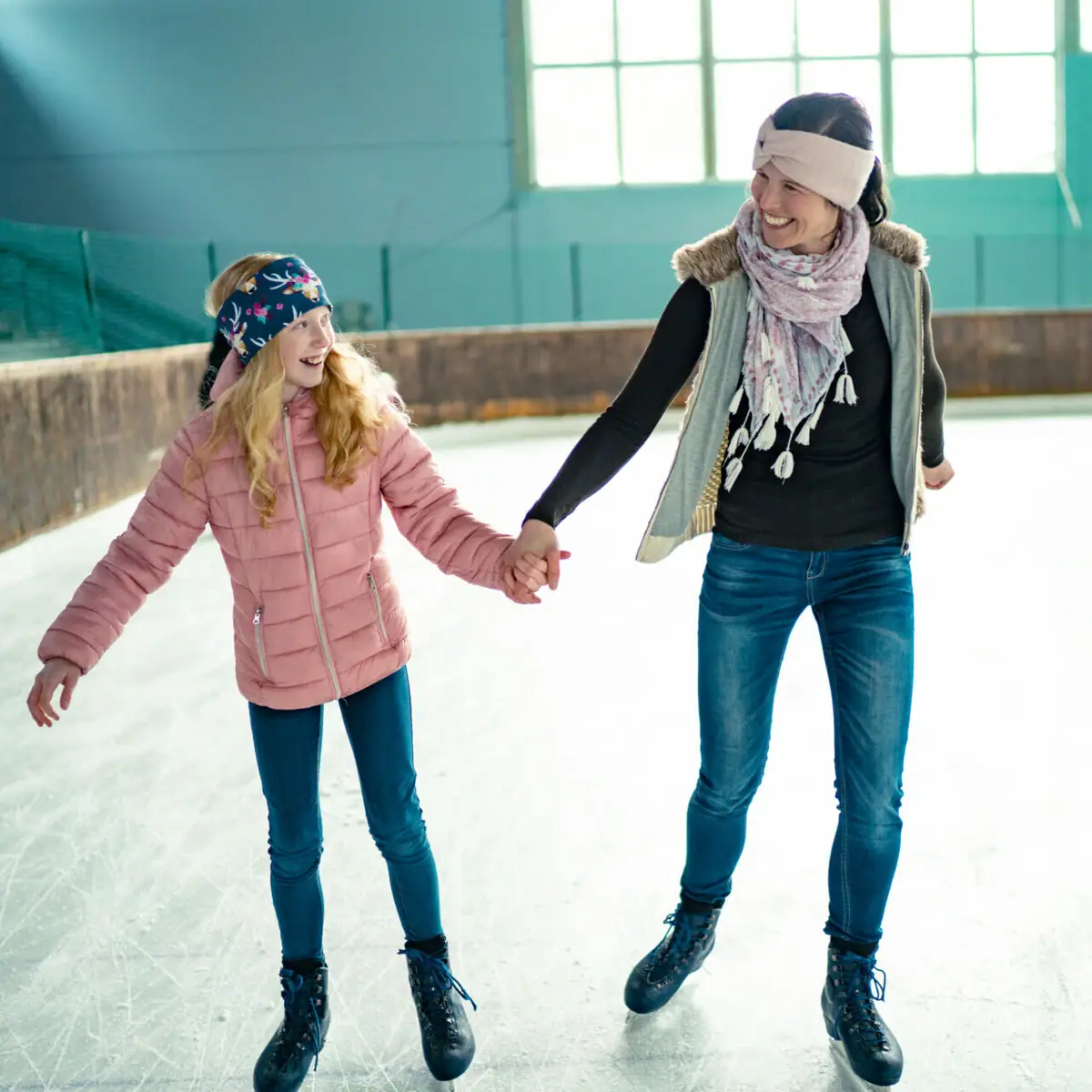 Schaatsen Een vrouw en een meisje houden elkaars hand vast tijdens het schaatsen.