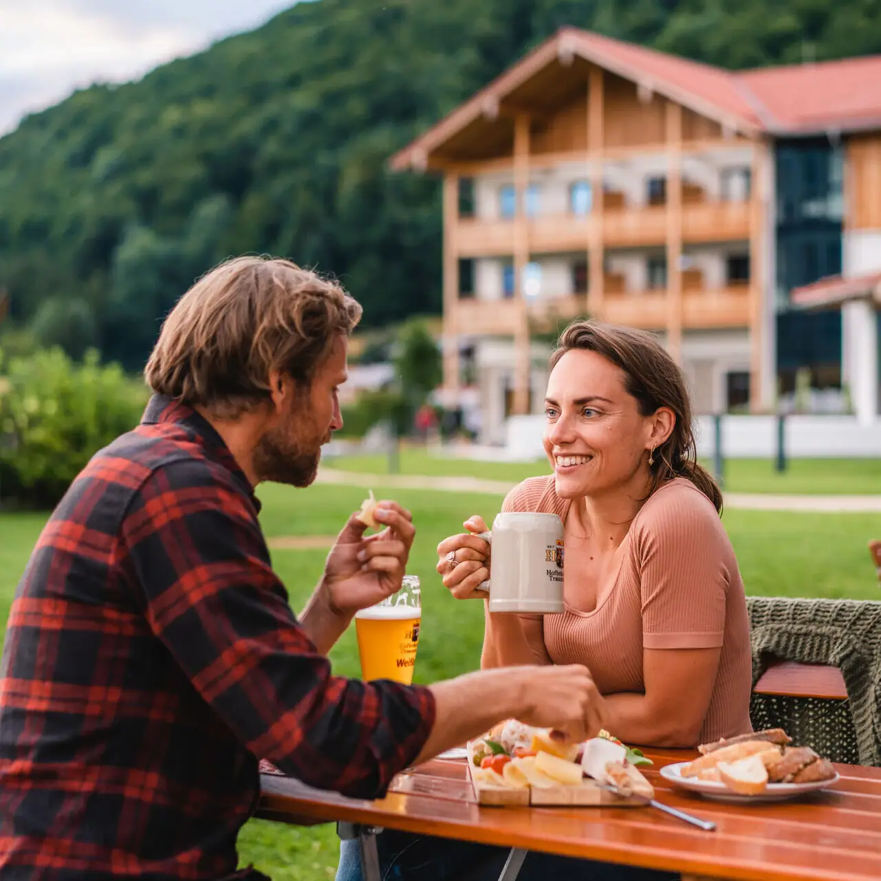 Een man en een vrouw zitten aan een tafel met eten en drinken.