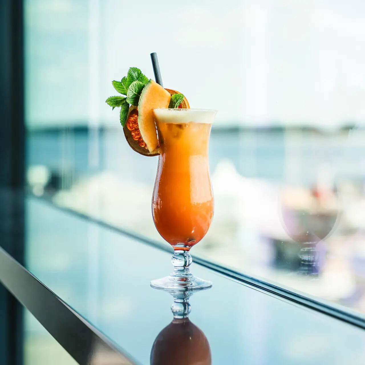 Cocktail Een glas met een cocktail en een garnering op tafel.