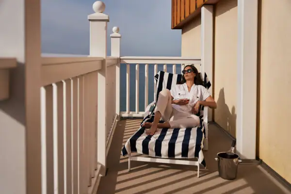 Een vrouw zit op een stoel op een terras.