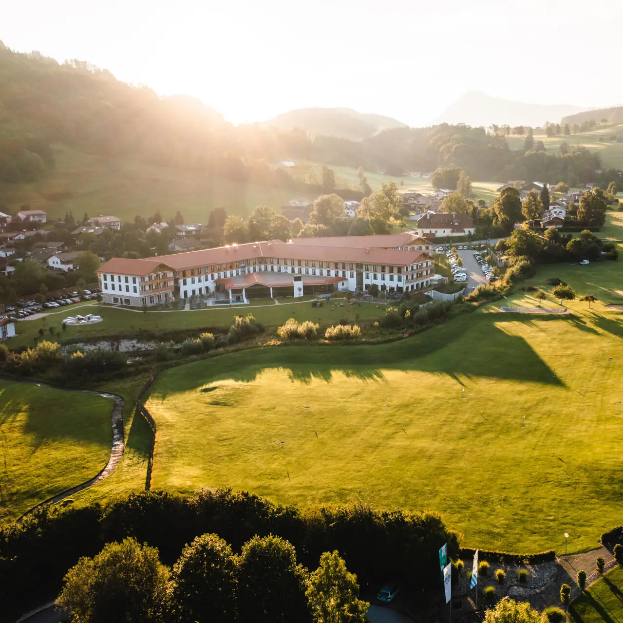 aja Hotel in Ruhpolding Groot groen veld met een gebouw en bomen op de achtergrond.