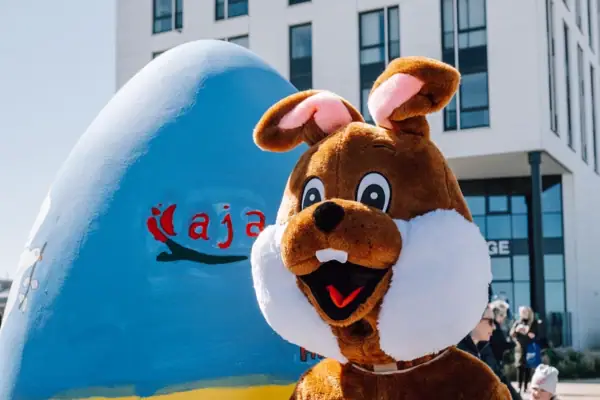 Persoon in konijnenkostuum naast een ei