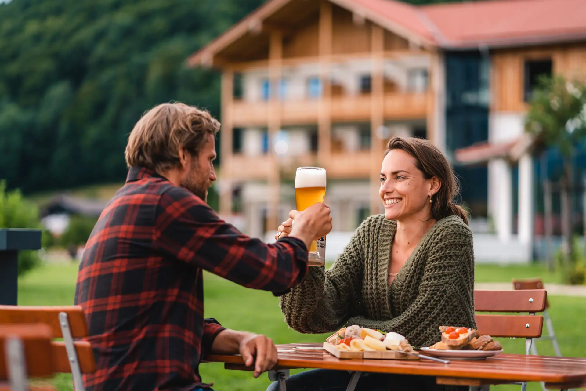 Een man en een vrouw zitten aan een tafel met eten en drinken.