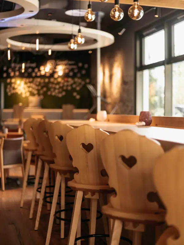Barkrukken De aja Bar Garmisch-Partenkirchen met stoelen en tafels.