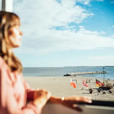 Een vrouw kijkt uit een raam op een strand.