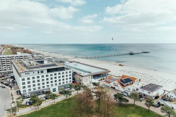 Strand met gebouwen en een pier op de voorgrond.