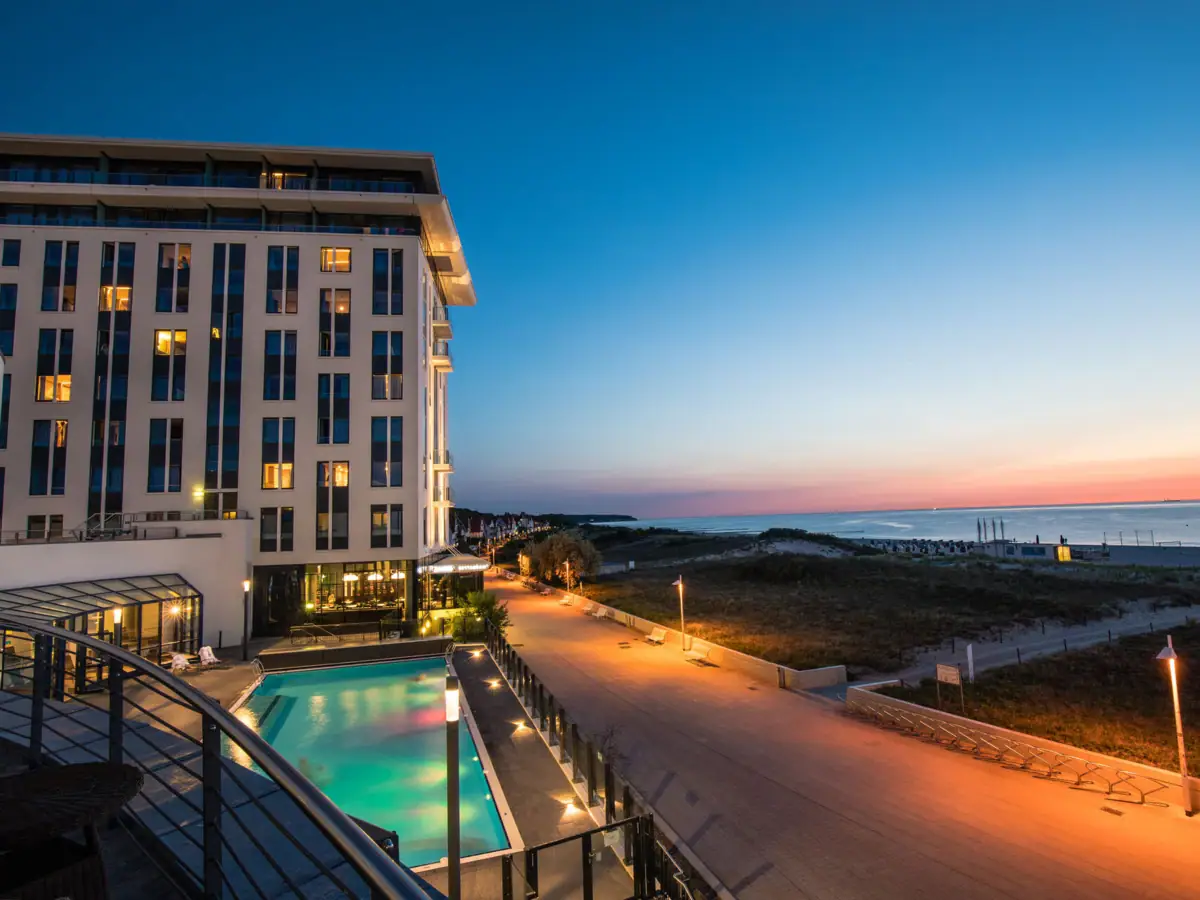Oudejaarsavond bij aja Warnemünde Het hotelgebouw met zwembad en wandelpad aan zee.