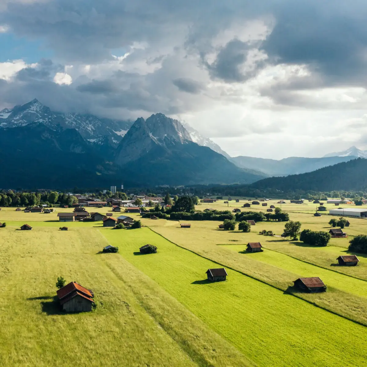 Groen veld met gebouwen en de Zugspitze op de achtergrond
