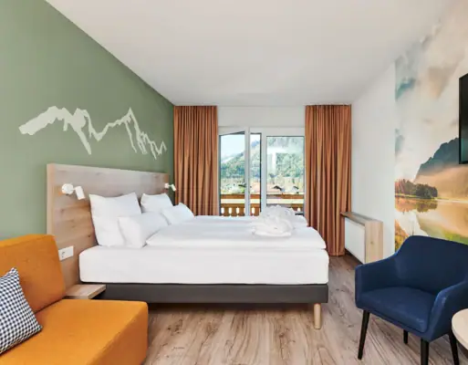 Tweepersoonskamer met balkon aja Ruhpolding Een kamer met een bed en een stoel.