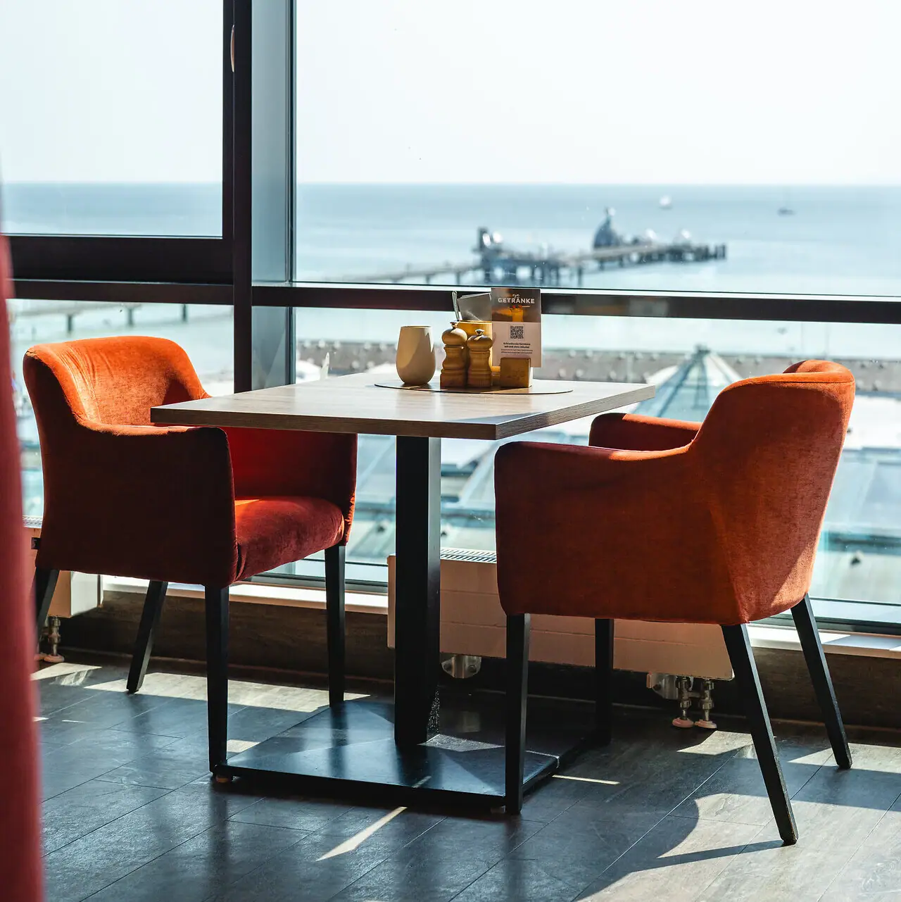 Restaurant bij aja Grömitz Een tafel met stoelen en uitzicht op zee.