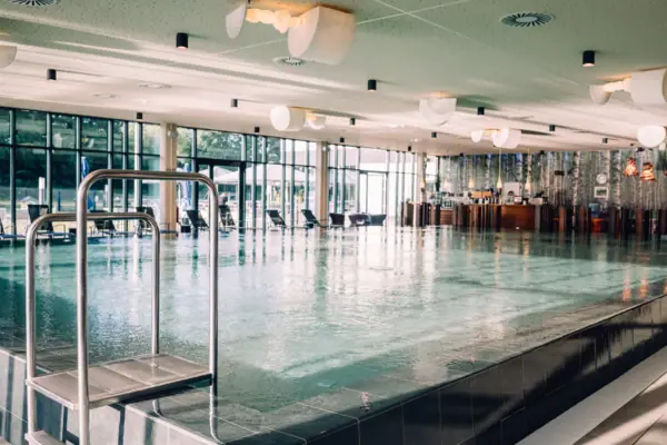 Groot overdekt zwembad met helder water en moderne architectuur.