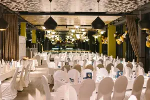 Oudejaarsavond kamer Een grote zaal met veel tafels en stoelen met witte hoezen.