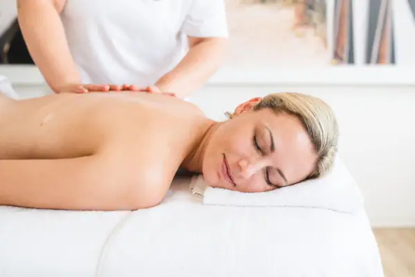 Vrouw ligt ontspannen op een massagetafel.
