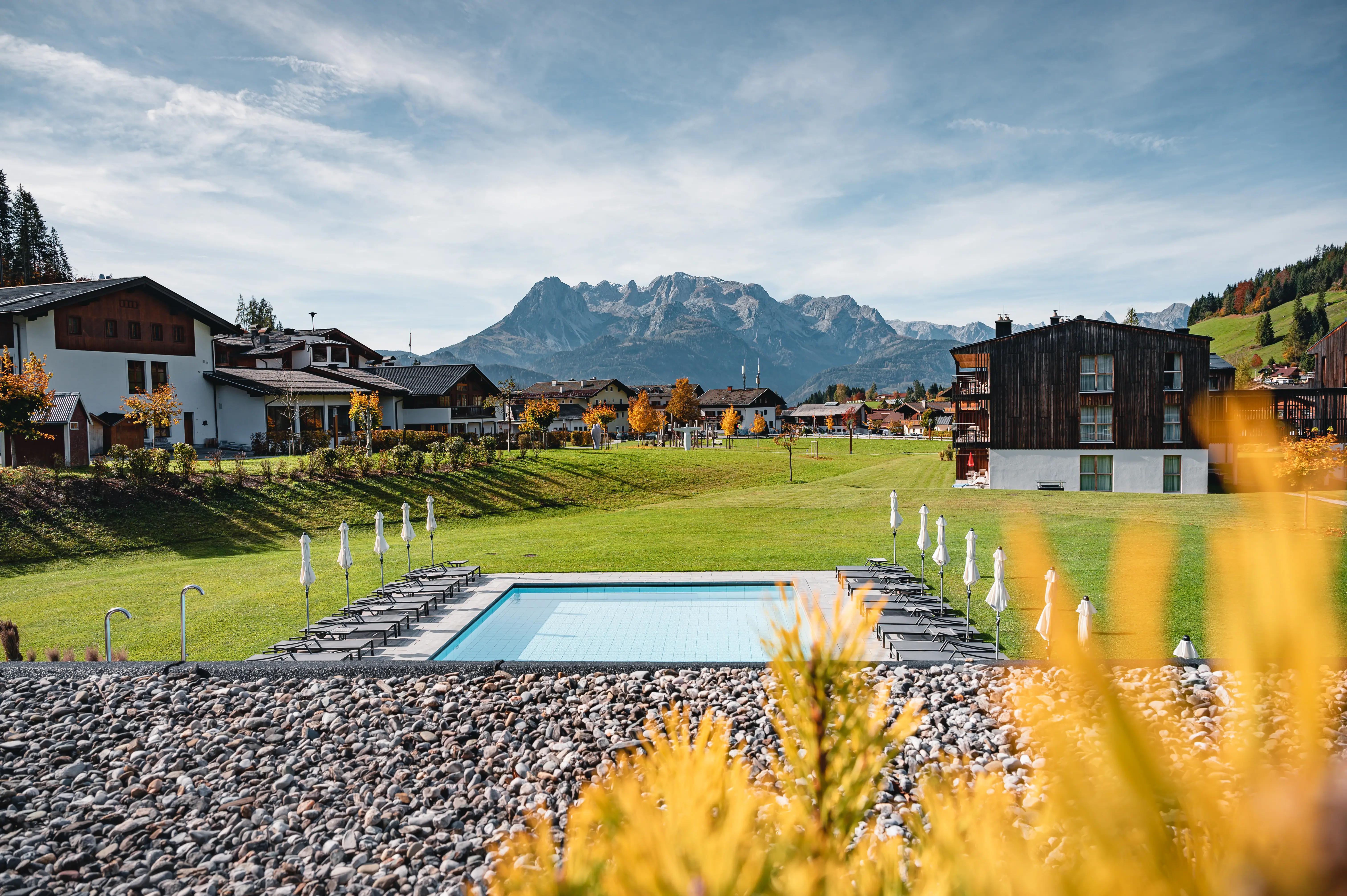 Werfenweng bekijken Een zwembad in een grasveld met bergen op de achtergrond.
