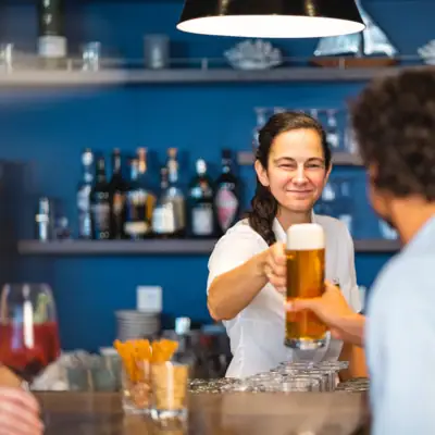 Bar in de aja Warnemünde Een vrouw houdt een glas bier vast en staat met een gast aan de bar.